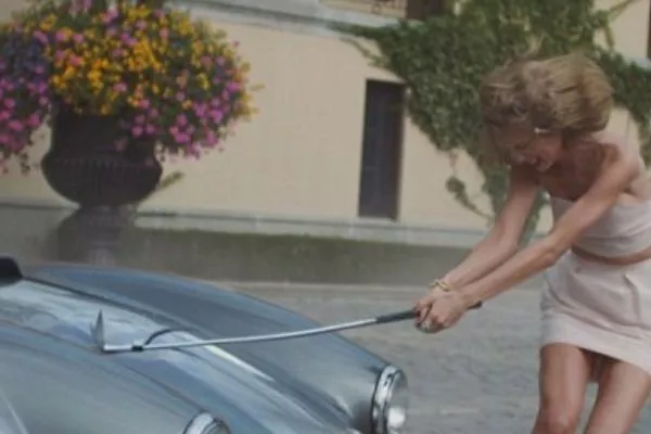 A picture of Taylor Swift swinging a golf club at a rare Shelby AC Cobra