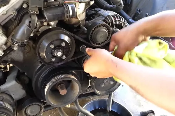 Use the owner’s manual to locate the routing diagram Man removing the belt of the car