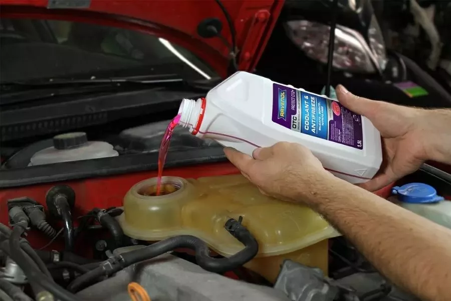 A picture of a man filling a coolant reservoir with coolant