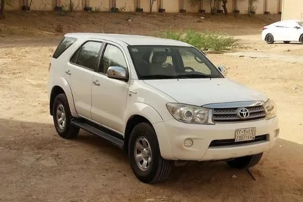 A picture of a first generation Fortuner on an unpaved parking lot