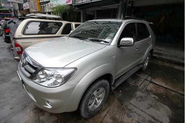 A picture of a 1st gen Toyota Fortuner parked near some businesses