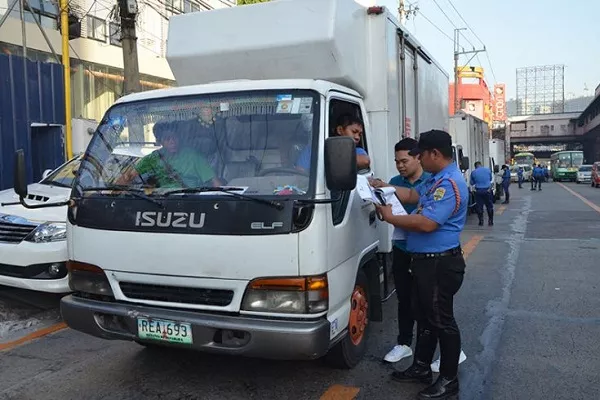 A picture of an MMDA enforcer issuing a ticket to a truck