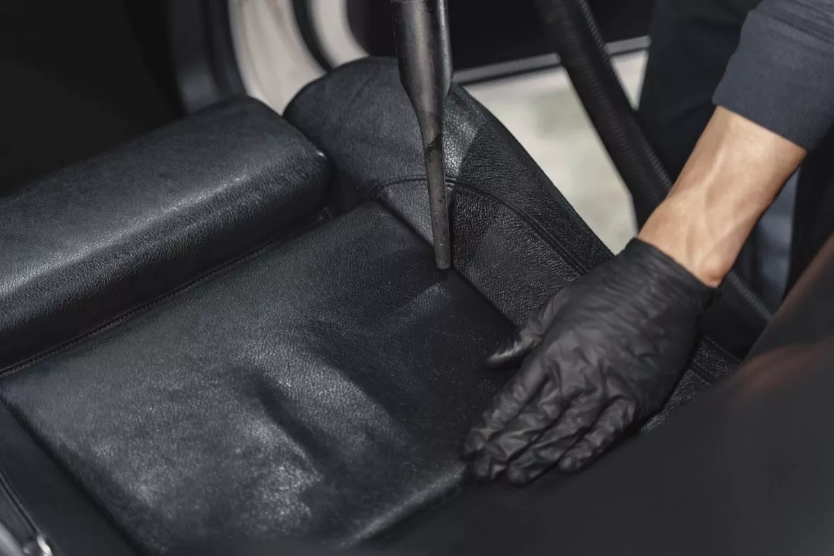 A picture of a man vacuuming his car interior