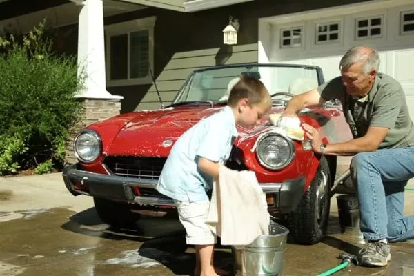 A picture of a man and kid washing a car