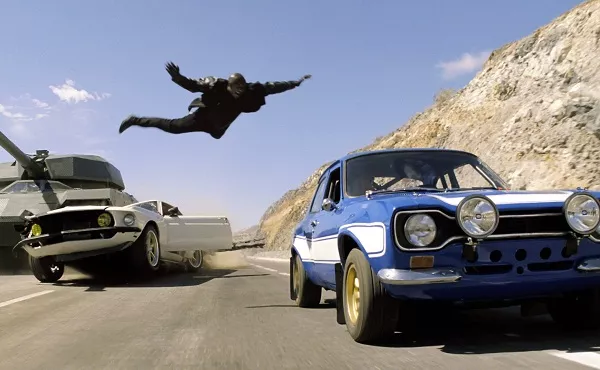 In California,it's illegal for anyone to jump from a moving car with a speed of 65 miles per hour. Man jumping from one car to another