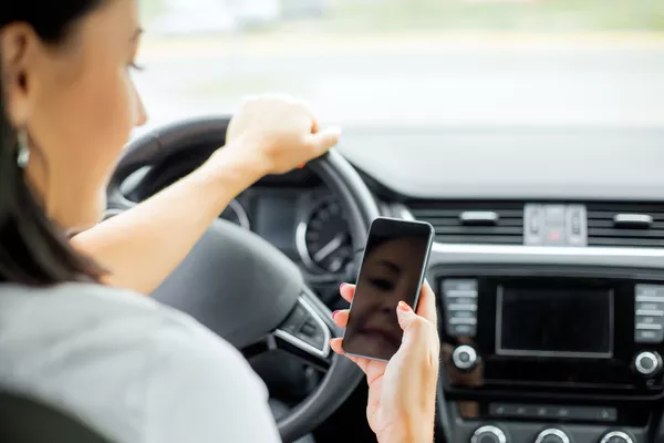 Keep clear of distractions like your phone or any other handheld device Woman texting while driving