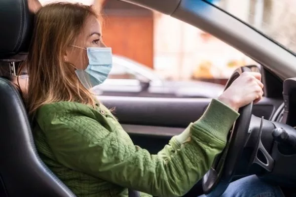 A picture of a woman wearing a face mask while driving