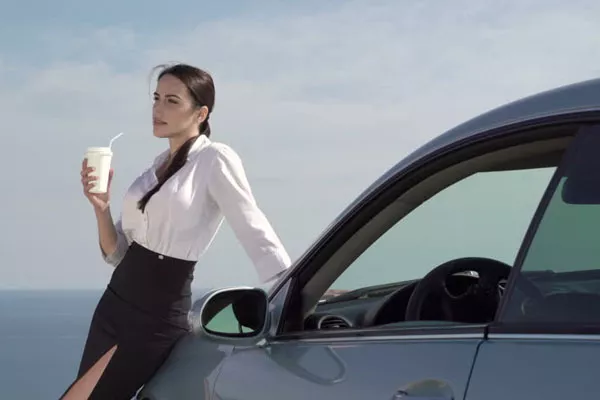 woman thinking leaning on her car