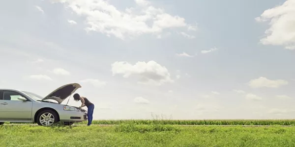 woman is looking into the car engine