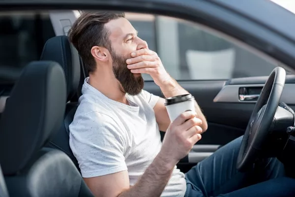 man yawning in car