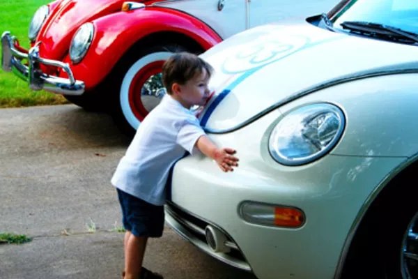 A young boy hugging his VW bug