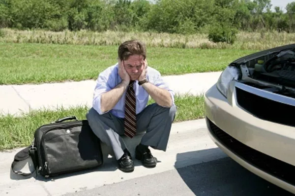 a sad man sitting outside his car
