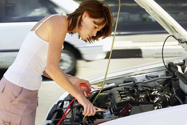 a woman checking her car's battery