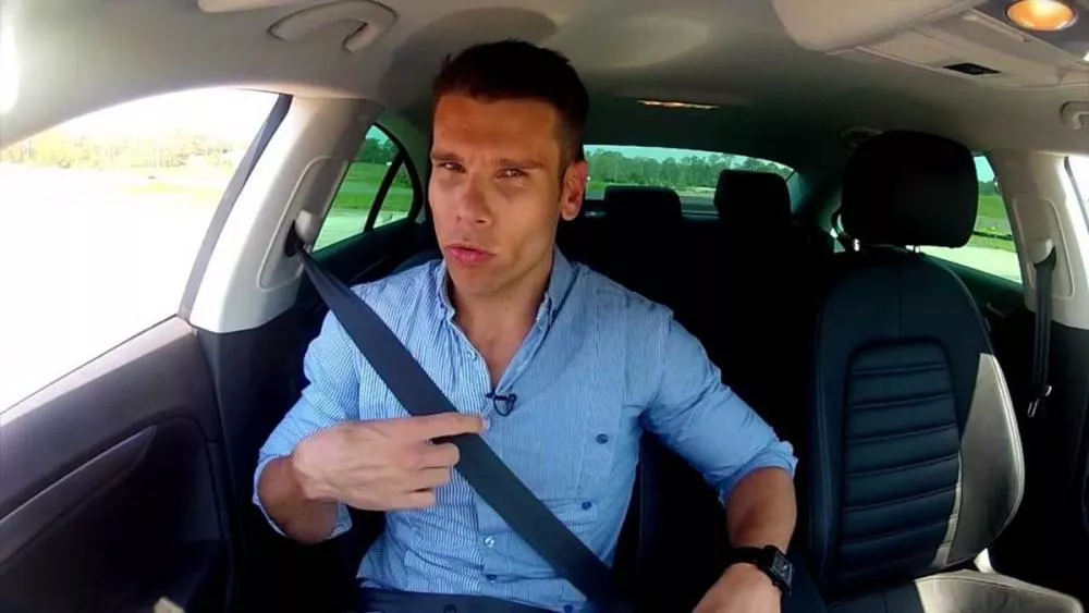 A guy buckling up before his drive.