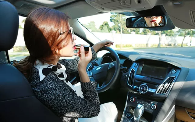 A woman in car putting on lipstick