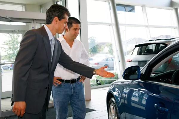 A car salesman introducing a car to his customer