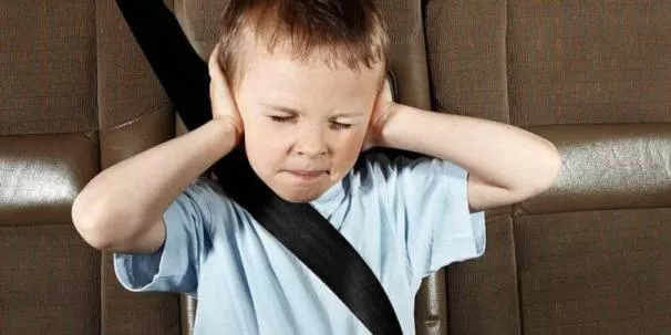 a child covering his ears in car