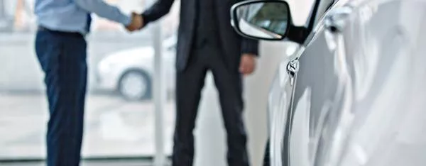 Two men shaking hands at car dealership