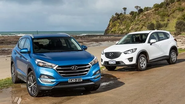 A blue and a white Hyundai Tucson in front of beach