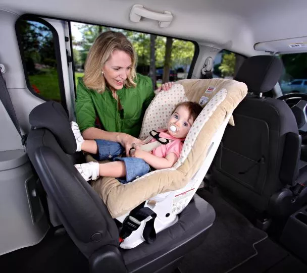 A woman putting her child to the rear-facing position