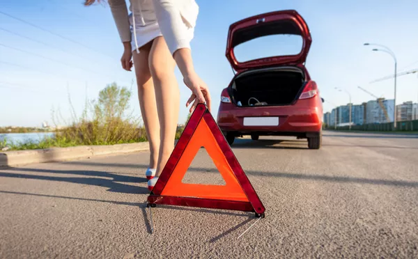 An early warning device is an obligatory accessory for cars Girl laying reflective warning triangle