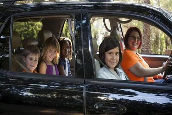 a woman driving a car taking some kids to school