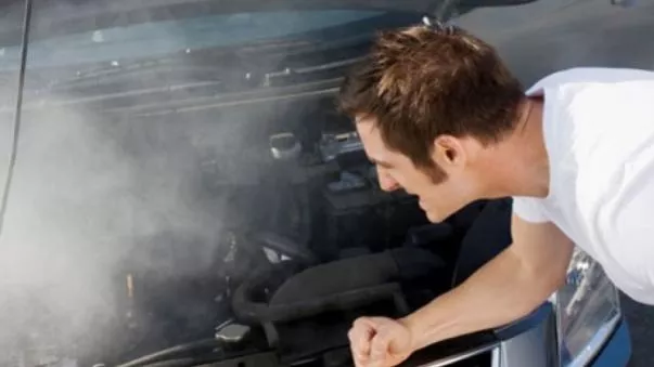 A man fixing his overheated car engine