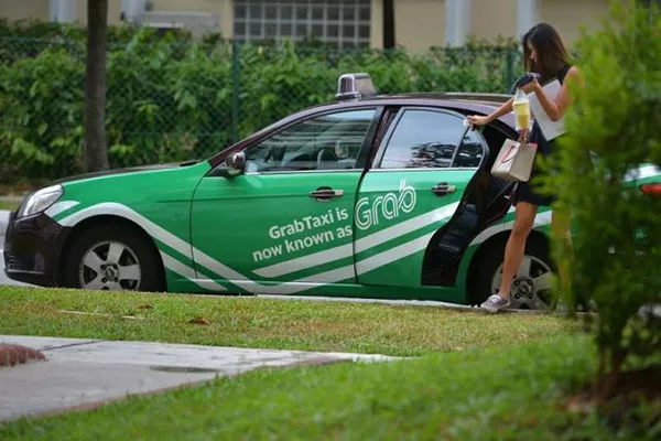 a woman getting out of a grab taxi