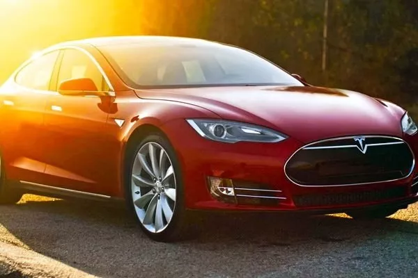 A red Tesla parked under the sun light