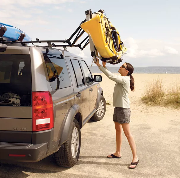 a girl loading stuff on the roof of her car