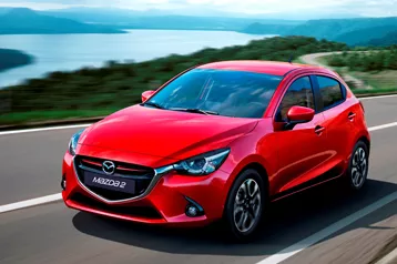 A red mazda 2 on the road