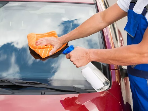 Removing a car sticker with microfiber towels and glass cleaner 