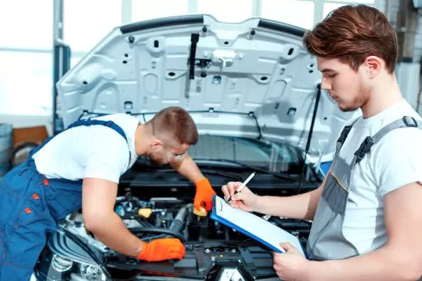 Two men inspecting under the hood of the car