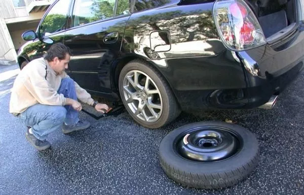 A man replacing car tire with spare tire
