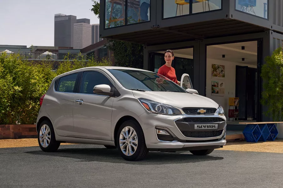 A picture of a woman together with her Chevrolet Spark