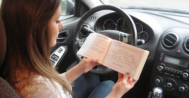 A woman reading the manual of the car