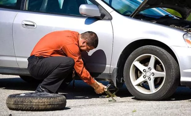 A man relacing his car's tire