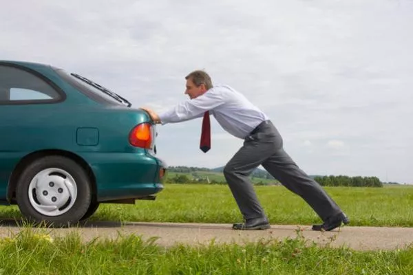 A man pushing a car