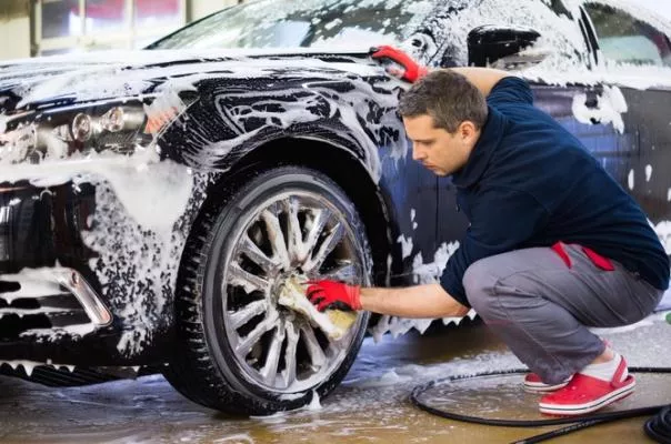 A man is washing a black car