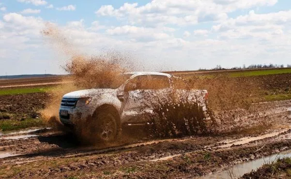 A white Ford Ranger crossing mud